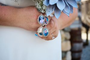 Blue floral wedding accessories and sentimental photo charms attached to a bridal bouquet.