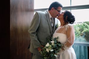 A couple shares an intimate moment with a bouquet in an elegant indoor setting.