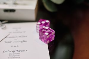 Purple wedding dice rest on a printed order of events program.