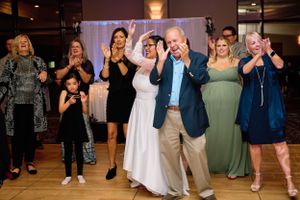 Wedding party guests celebrating and cheering on a dance floor at a reception.