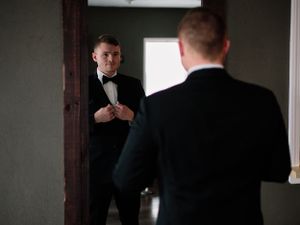 Elegant scene of person adjusting bowtie while looking in mirror before formal event.