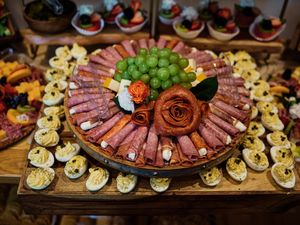 Elegant charcuterie board displays arranged meats, cheeses and appetizers on wooden serving platters at a catered event.