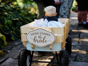 A decorated wagon with 'Here Comes the Bride' sign sits ready for the wedding ceremony.
