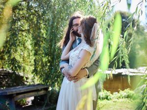 A tender moment captured between two people embracing under a weeping willow tree.