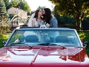 A couple shares a romantic moment in a classic red convertible car.