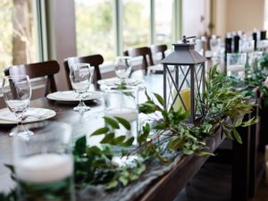 Elegant wedding table setting with lantern centerpiece and greenery garland decor.