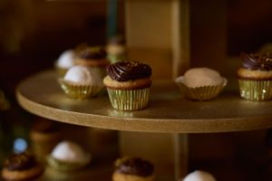 Artistically lit chocolate cupcakes displayed on a gold tiered dessert stand.