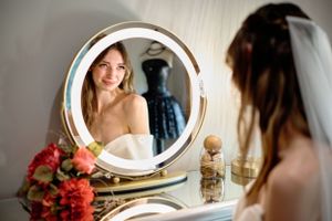 Elegant bridal preparation scene with vanity mirror and floral bouquet.