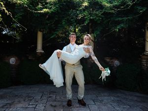A couple in wedding attire shares romantic moments in a wooded outdoor setting during their special day.