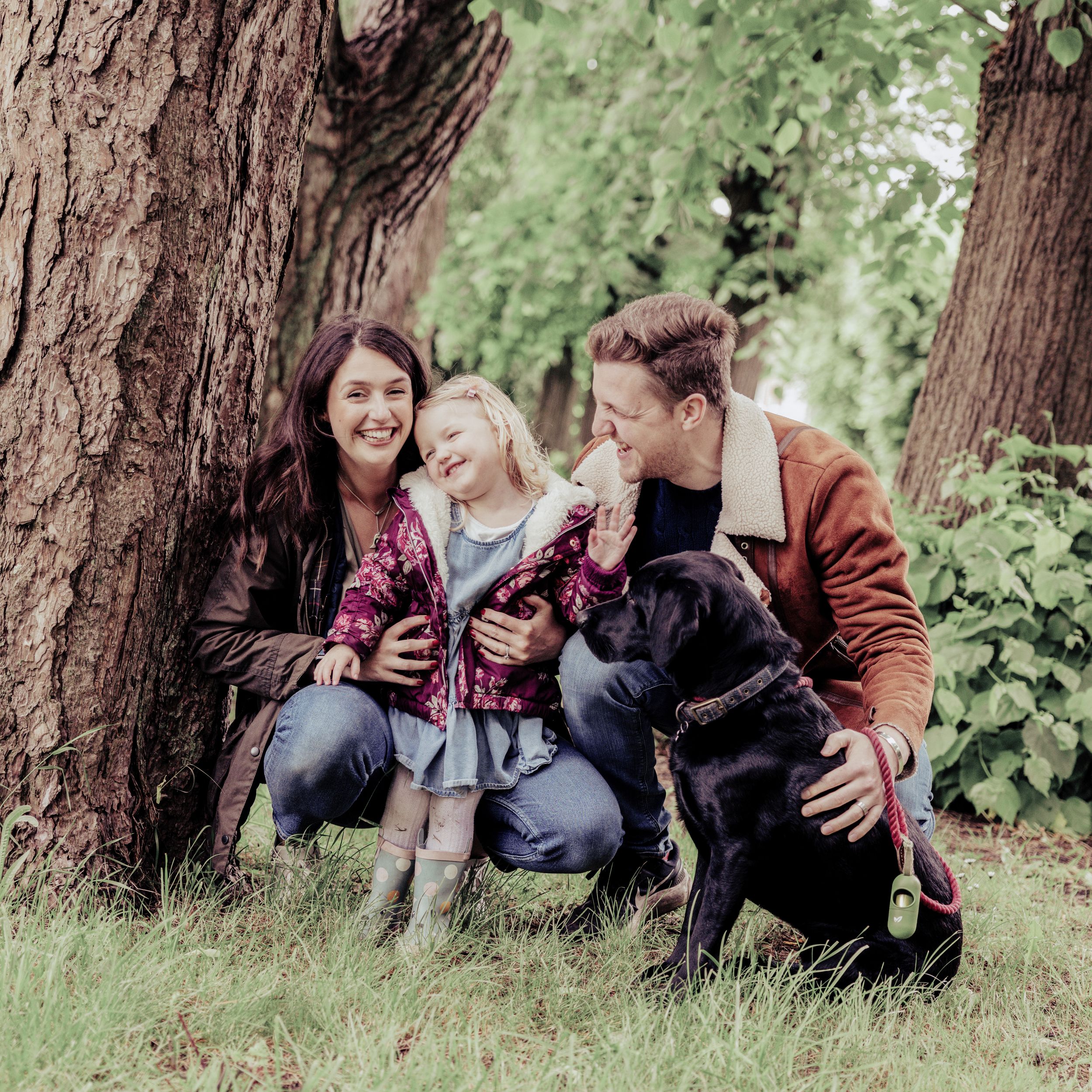 Relaxed family photoshoot with parents and child sitting together outdoors, capturing authentic connection and joy.