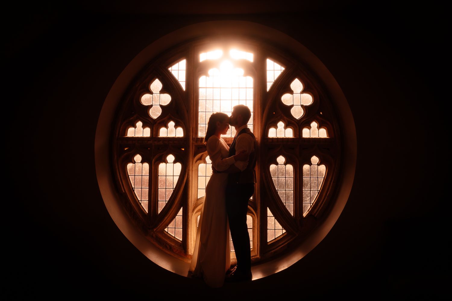 Silhouettes against illuminated round church windows create dramatic lighting patterns in dark space.