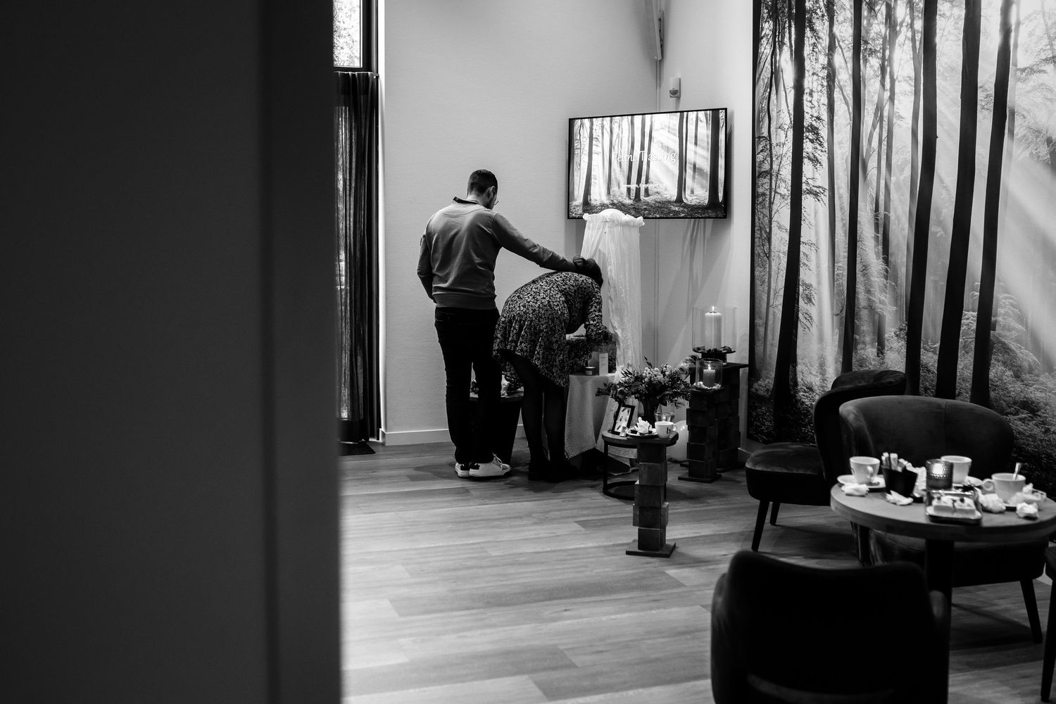 A black and white photo showing people setting up decorations in a room with hardwood floors.