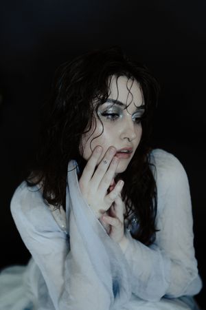 A series of dark moody portraits showing someone with messy dark hair in a white shirt against a black background.