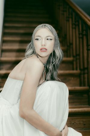 A woman in white poses elegantly against a wooden staircase backdrop in a series of artistic portrait shots.