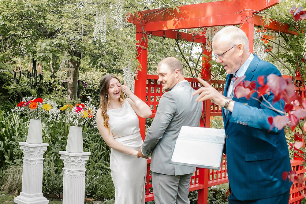 A couple shares romantic moments in a garden setting with red decorative elements and white statues.