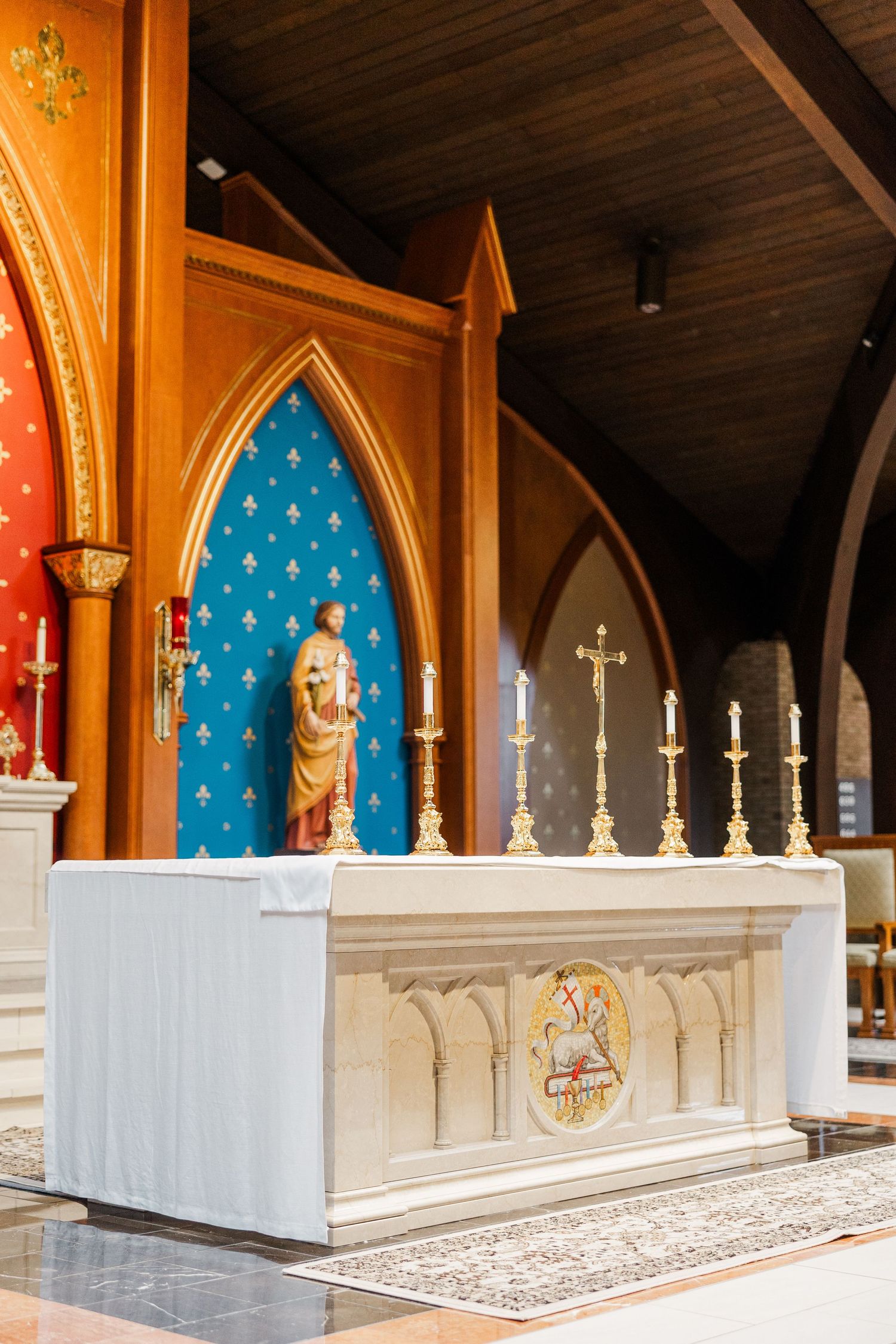 Interior of a church with ornate gothic arches decorated with red and blue panels and white marble altar railings.