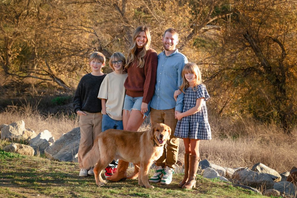 A group enjoying an outdoor photoshoot with a majestic mountain lion in a natural desert setting at sunset.