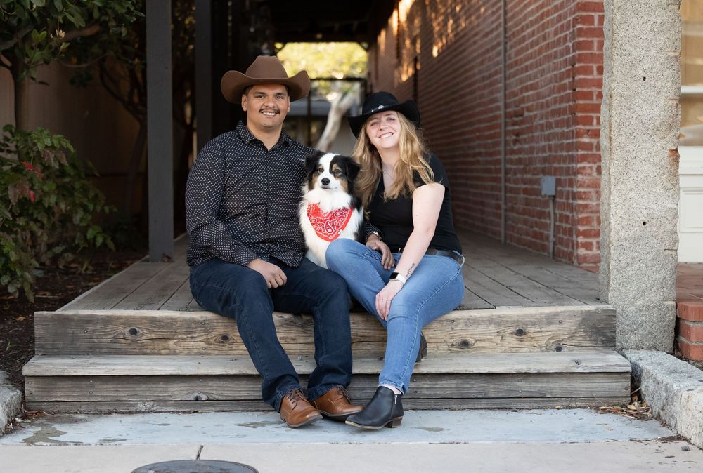 Couple sits together in a rustic brick alleyway during an outdoor photo session.
