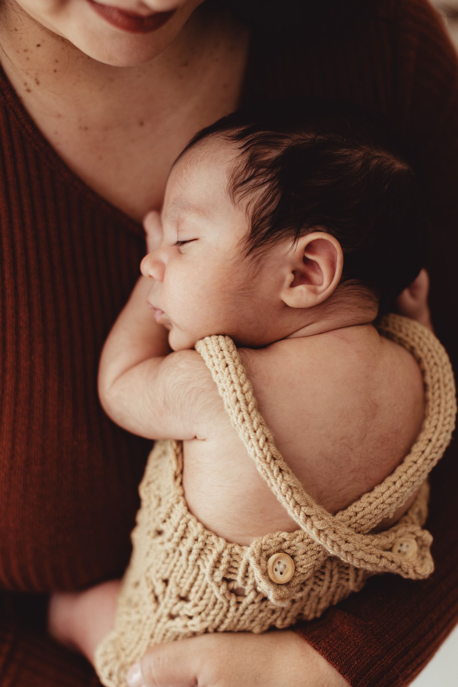 Newborn wearing delicate cream knit collar accessory in artistic portrait.