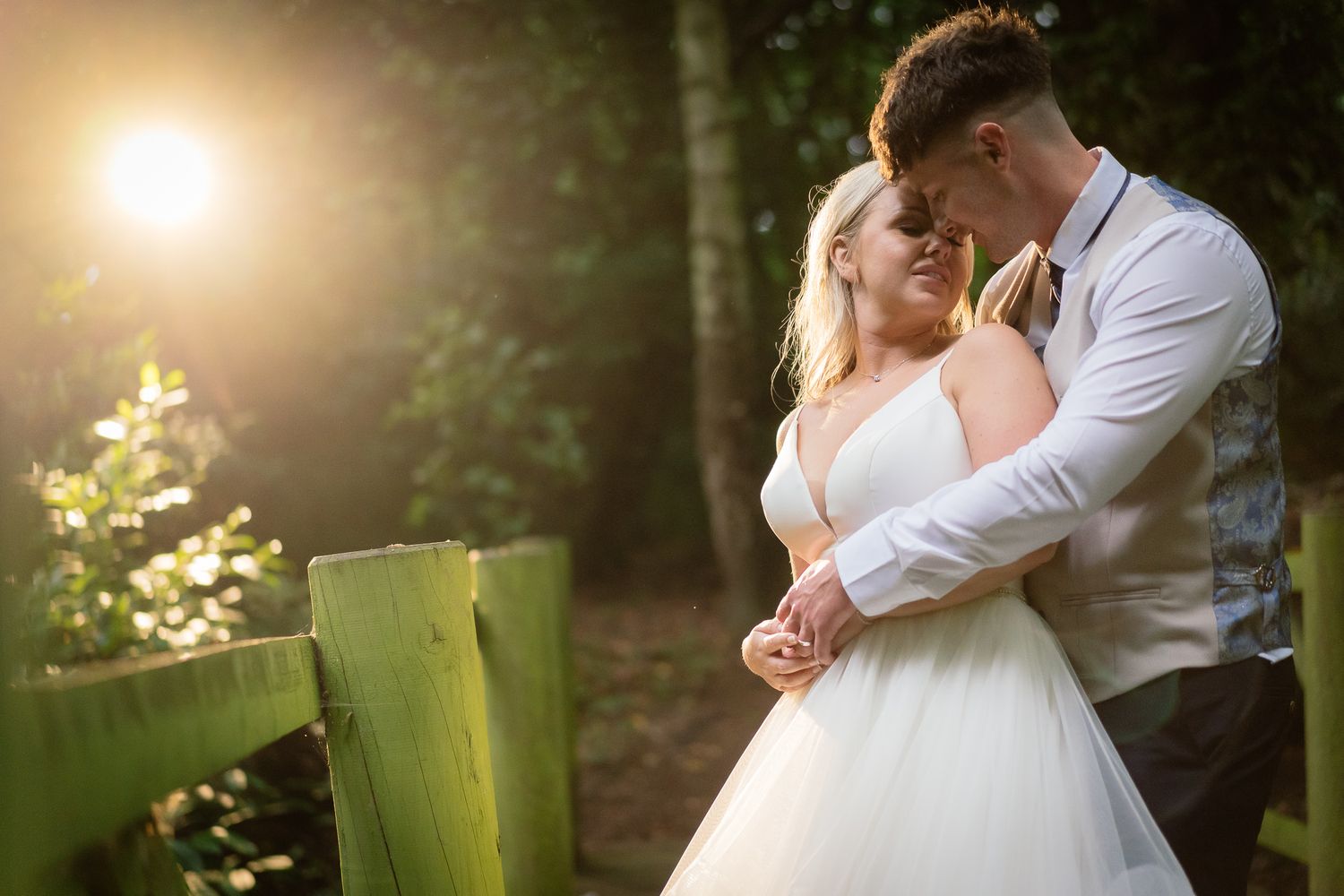 Intimate wedding portraits captured in a sunlit forest with natural greenery. Ellingham Hall
