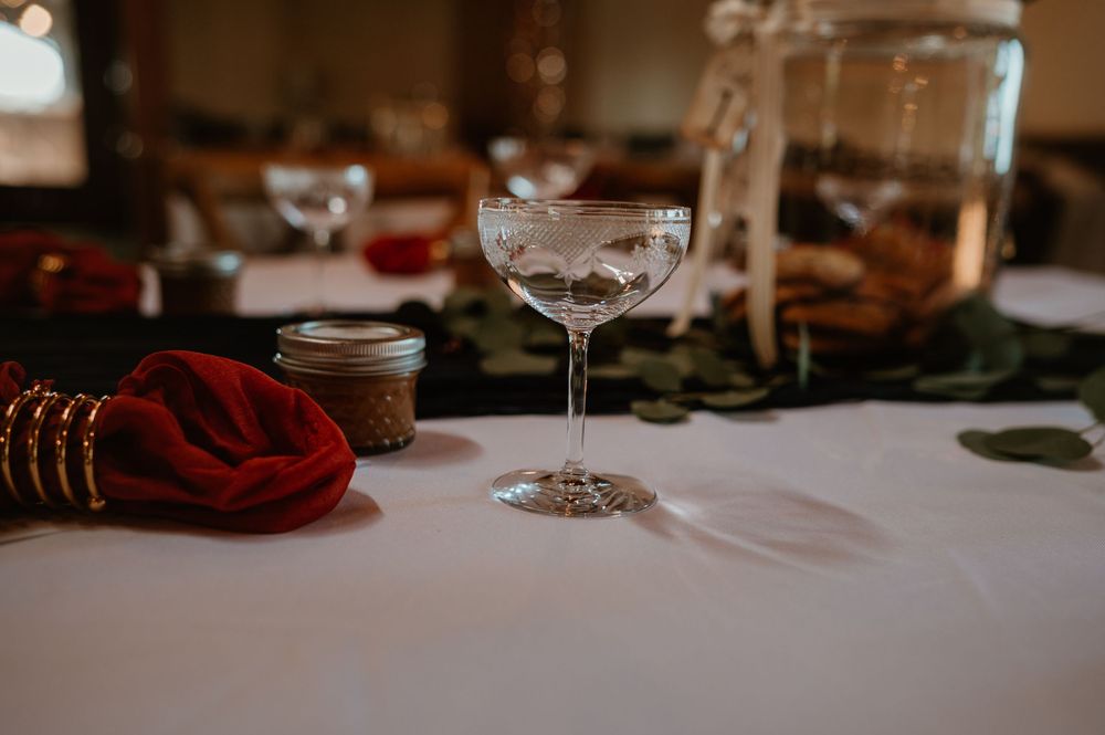 Wedding reception table settings with wine glasses and burgundy accents.
