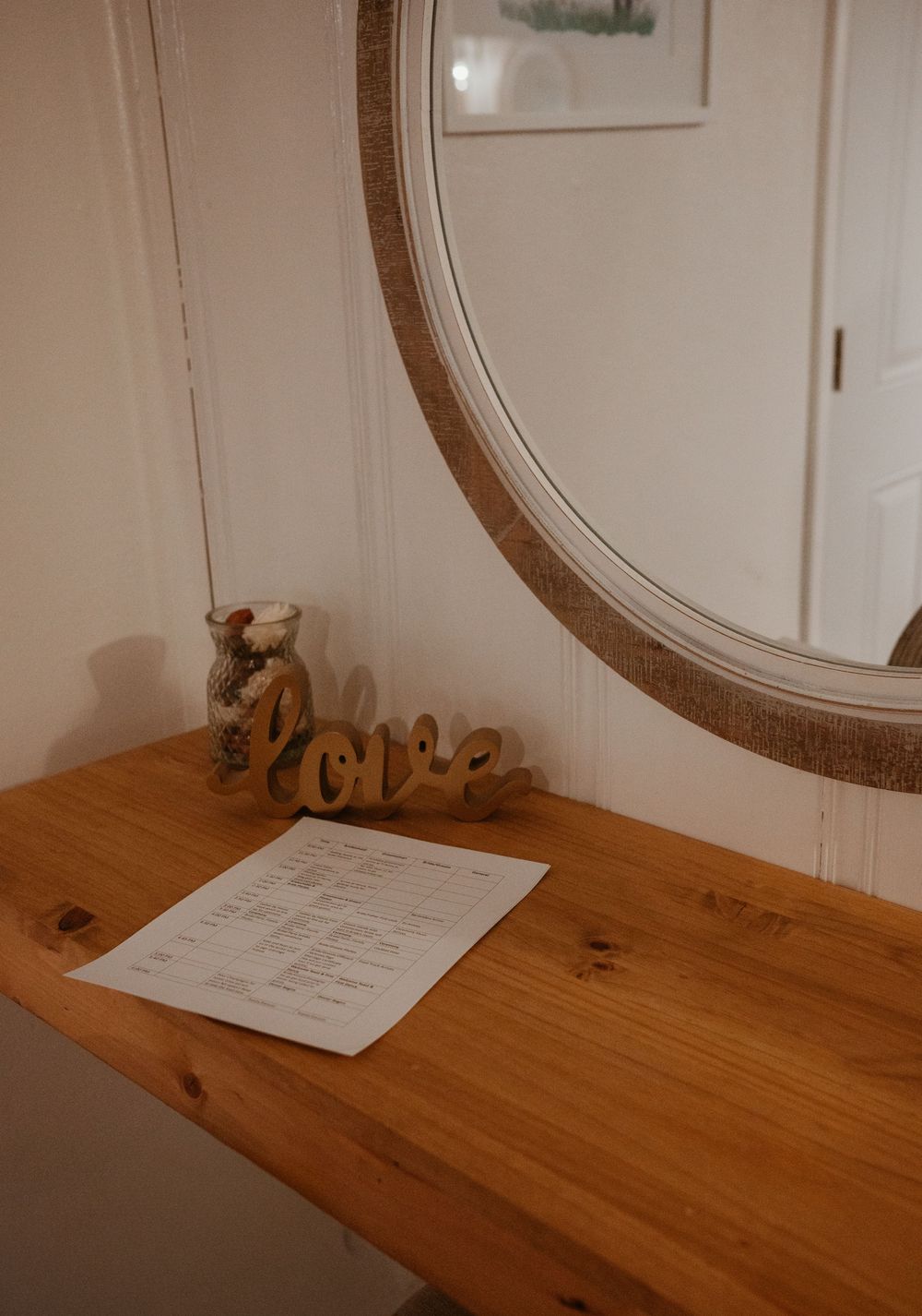 Wooden vanity table with mirror and decorative 'love' text in rustic wedding venue setting.