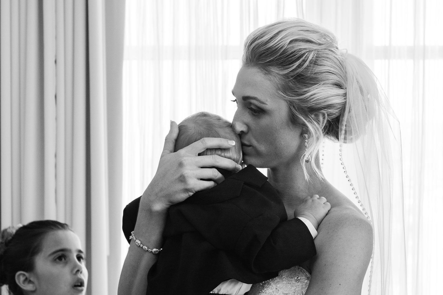 Emotional wedding moment captured in a bright, window-lit room.
