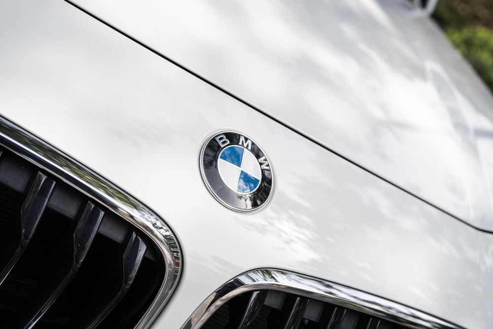 Close-up view of a white BMW car's hood showing the iconic BMW emblem and grille details.