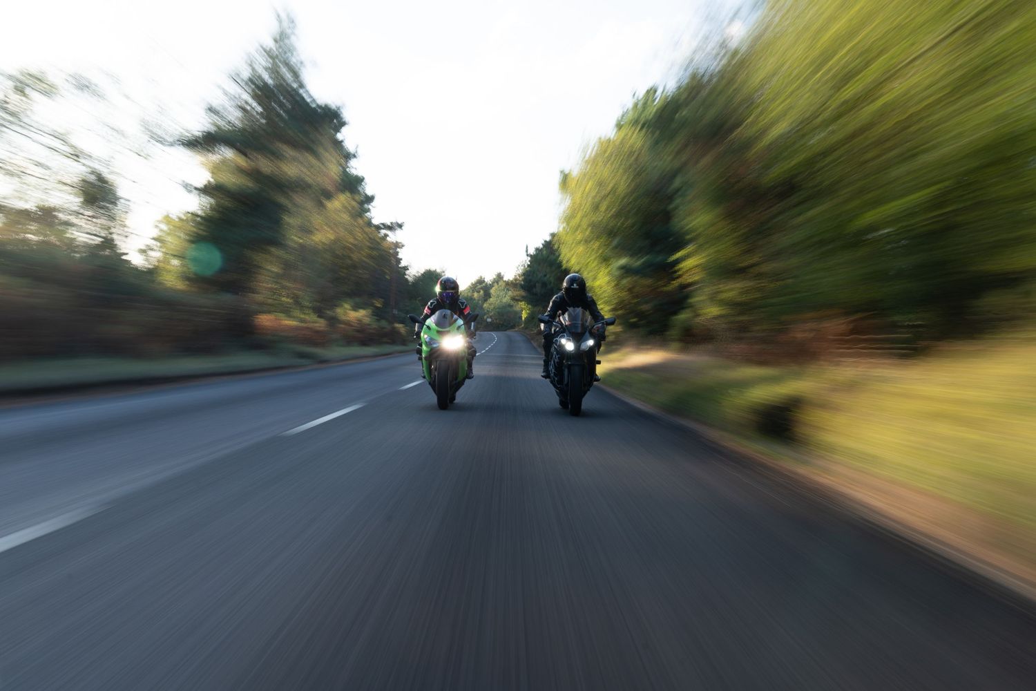 Motion-blurred view of motorcycles riding on a scenic road.