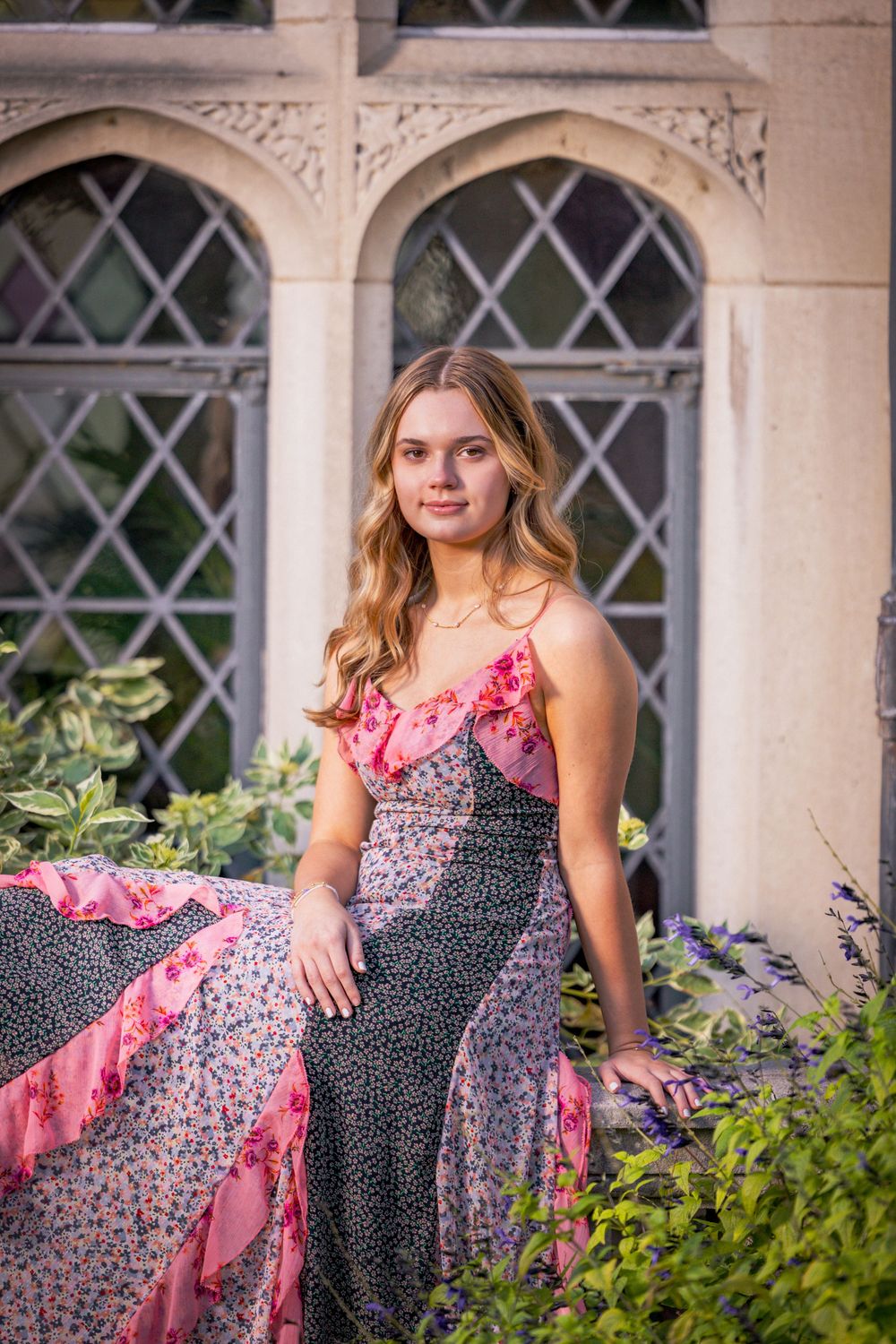 Portrait series featuring a pink and black patterned dress in an elegant garden setting with ornate windows.
