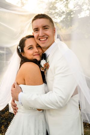 A happy couple shares intimate embraces in their wedding attire against a soft, dreamy background.