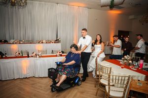 Wedding guests enjoy dancing and celebrating at an indoor reception with warm amber lighting and white curtained walls.