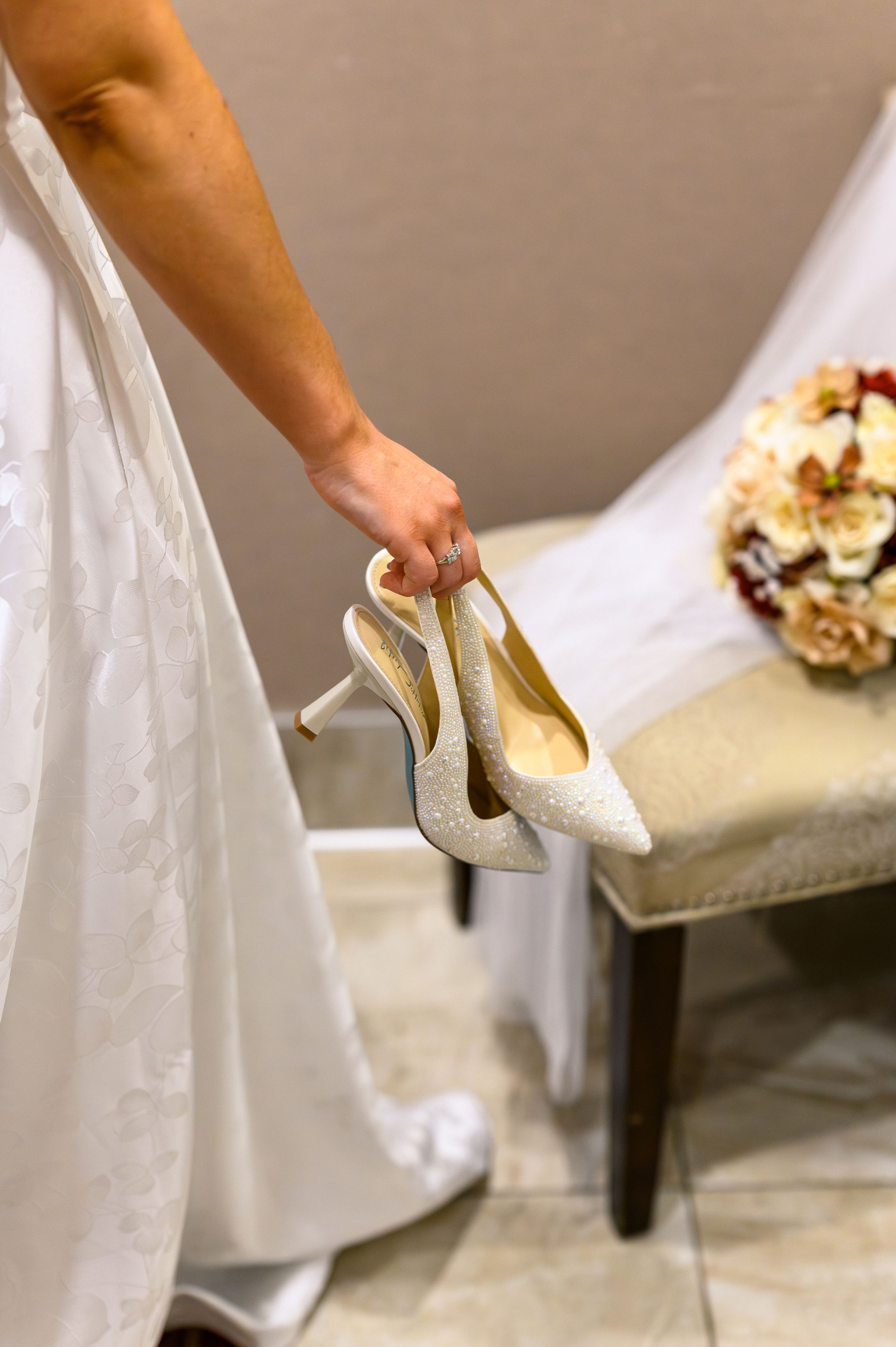 A sequence of close-up shots showing hands putting on sparkly white wedding heels with a bridal gown in the background.