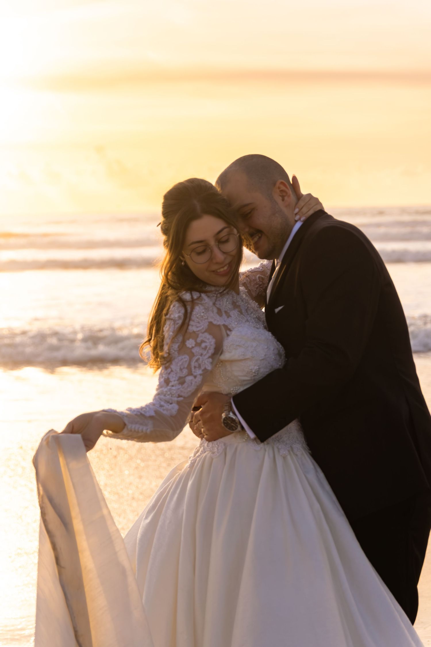Romantic sunset beach wedding photoshoot with couple in formal attire.