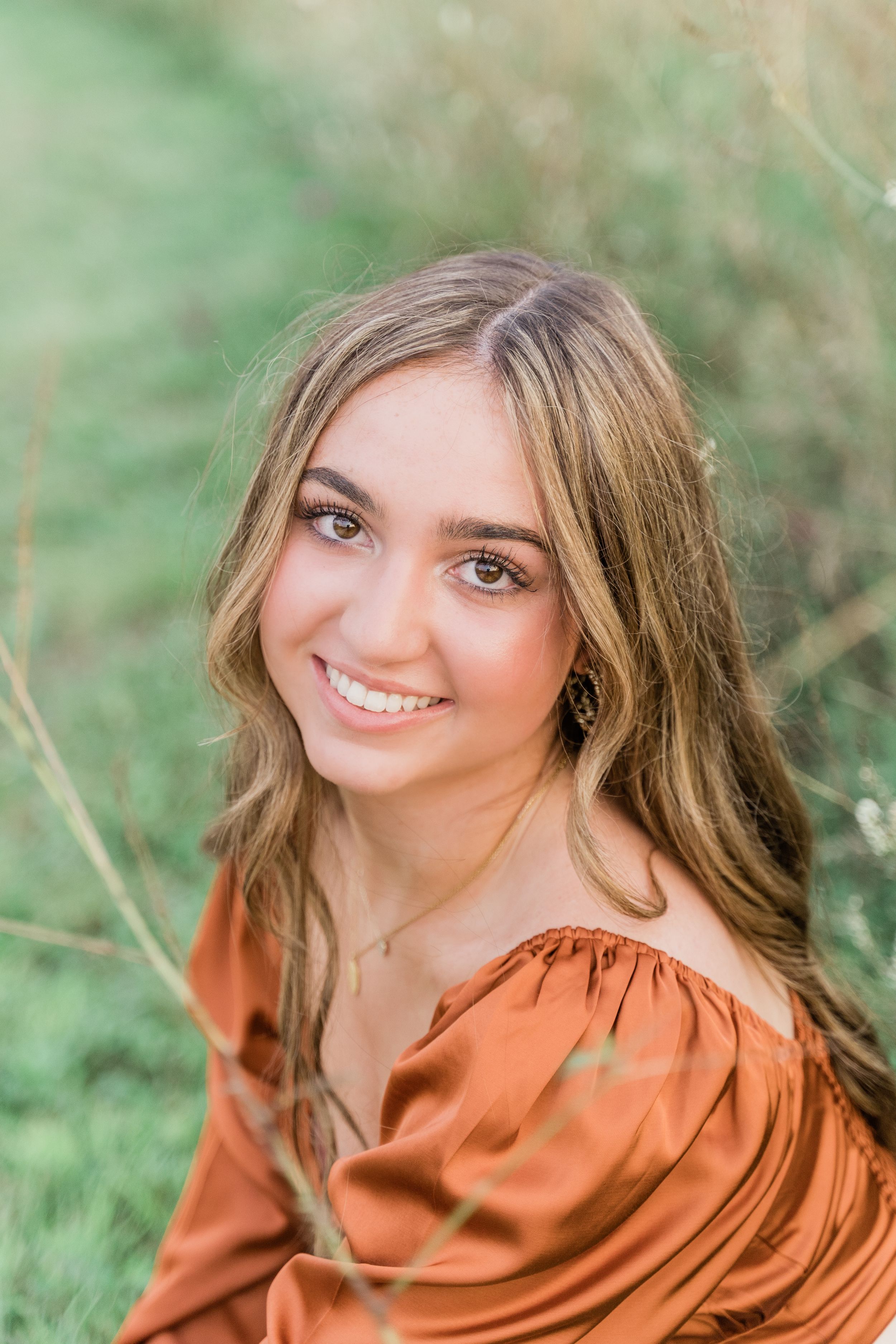 Close-up portrait shots showing someone wearing an orange top against a soft green natural background.