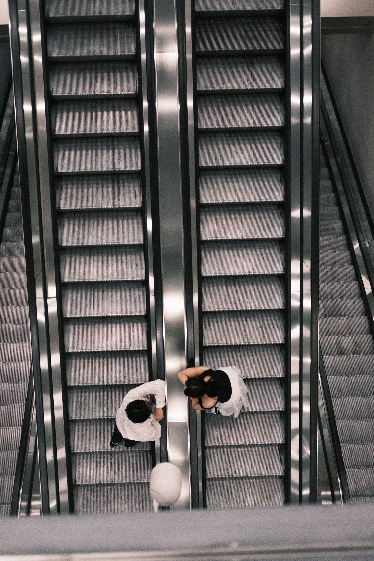 Multiple escalators moving in opposite directions create a modern geometric pattern in a minimalist setting.