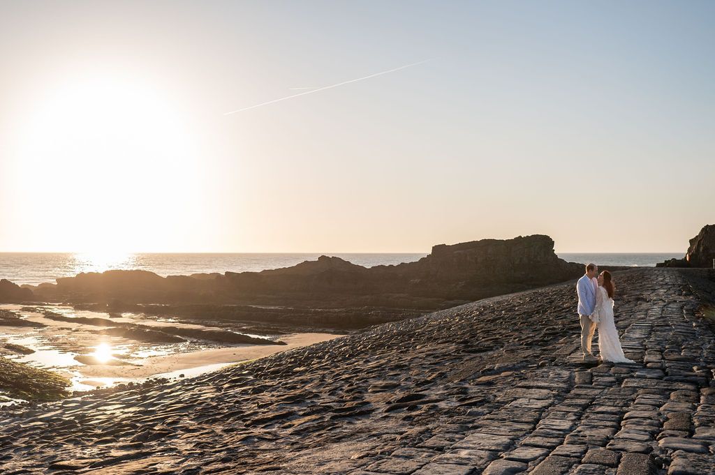 Just married couple on the Bude breakwater at the end of the beach at sunset