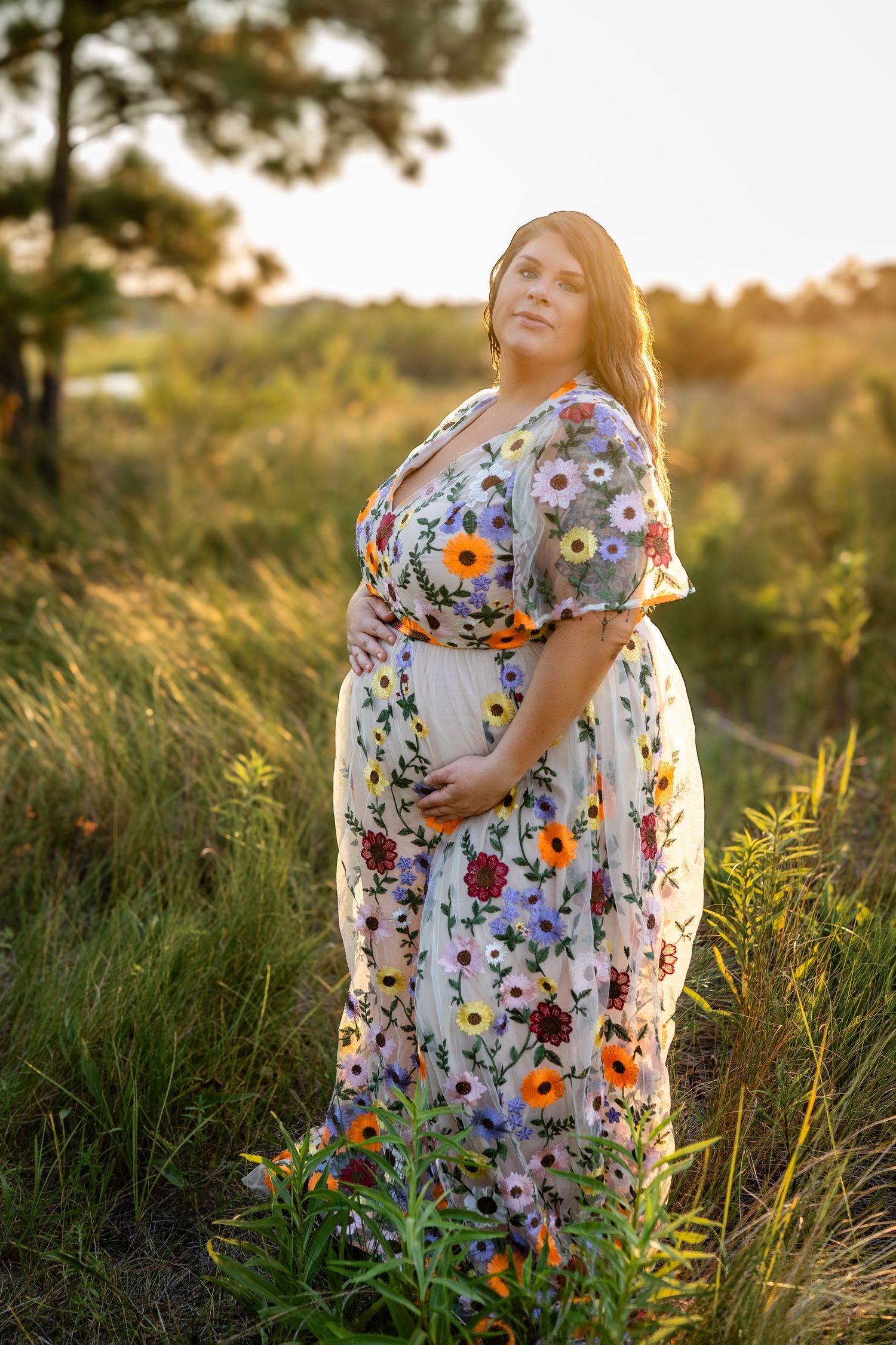 A floral dress flows in the golden sunset light among tall grasses in a dreamy outdoor setting.