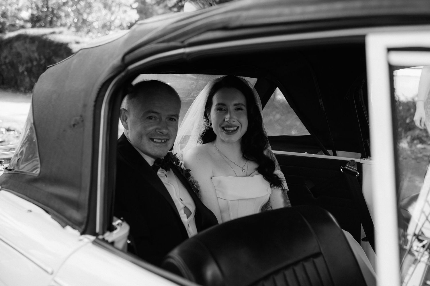 A vintage black and white photo collage showing people smiling inside classic cars during what appears to be a wedding.