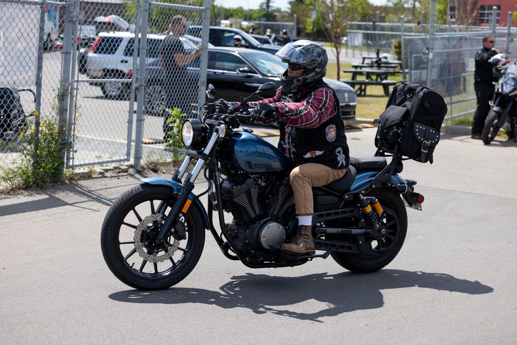 A row of custom motorcycles parked outside in a sunny parking lot showing various styles and models.