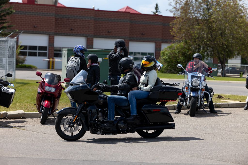 A row of vintage motorcycles and classic cars parked in a line at an outdoor show event.