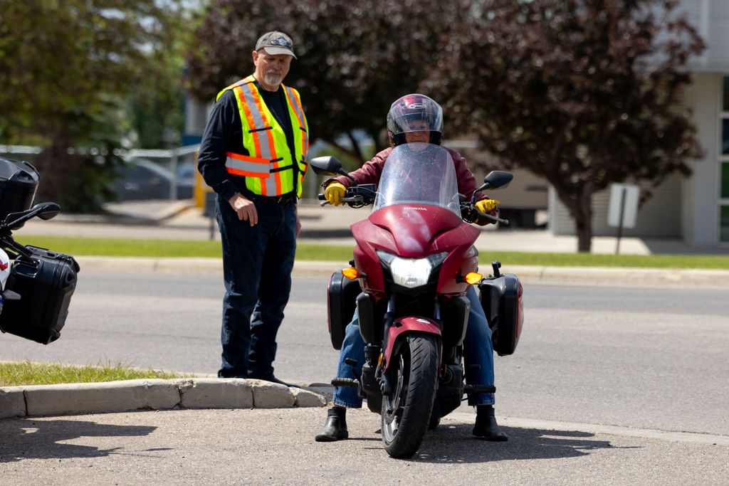 Motorcycle riders gathering in parking area wearing safety vests and helmets before group ride.