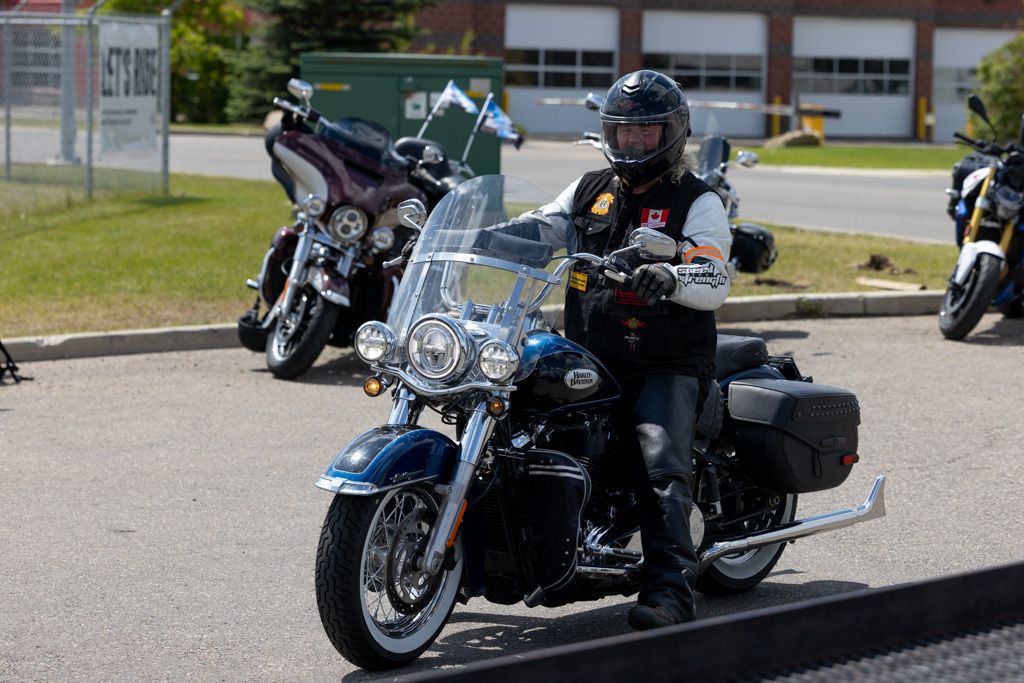 A row of motorcycles parked outside a building on a sunny day, showcasing various models and styles.