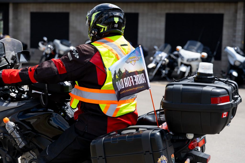 A row of parked motorcycles with helmets and safety gear visible in an outdoor setting.