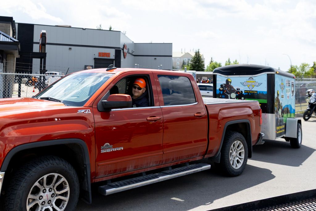 Red GMC Sierra pickup truck being loaded onto an auto transport trailer for shipping.