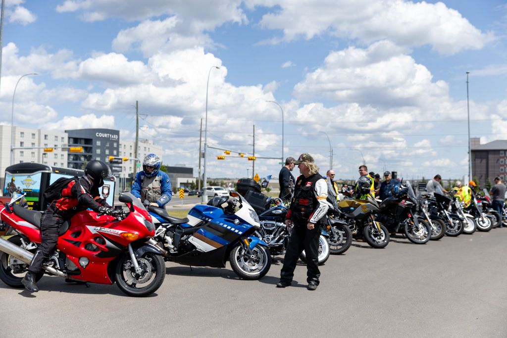 A row of colorful motorcycles parked in a line under blue skies with white puffy clouds on a sunny day.