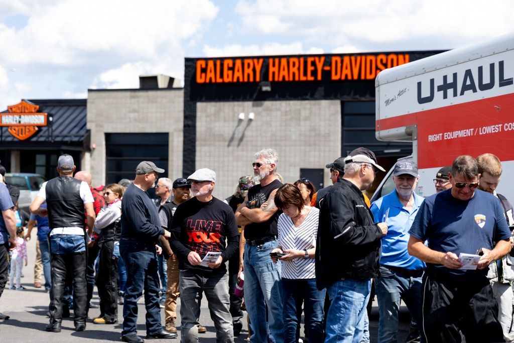Motorcycle riders and enthusiasts lined up outside a Harley-Davidson dealership in Calgary.