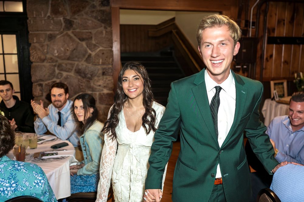 Group of people wearing formal attire including green jackets at a social gathering in an indoor venue.