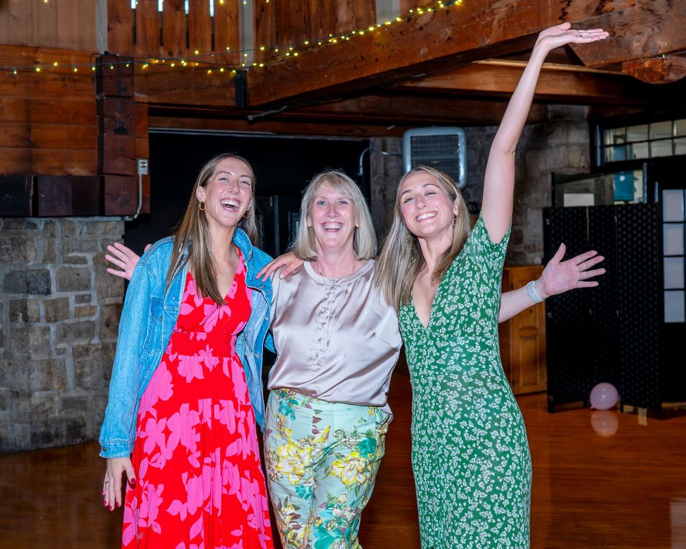 People dancing and having fun together at a rustic barn venue with string lights overhead.