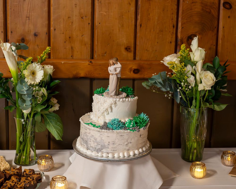 Rustic wooden wall backdrop with white floral centerpieces and candles arranged for an elegant wedding reception.